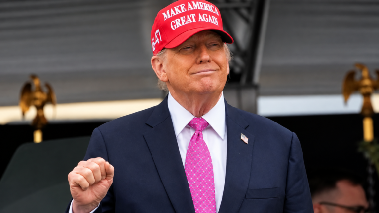 Donald Trump na podiu s cervenou siltovkou
